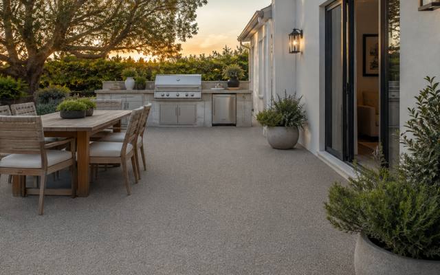 Backyard dining patio finished in sand-coloured rubber surfacing at sunset