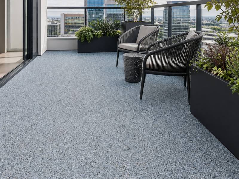 Condo balcony finished in light grey rubber surfacing with chairs and planters